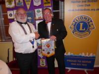 Lions President Brian exchanges bannerettes with visiting Swadlincote President 